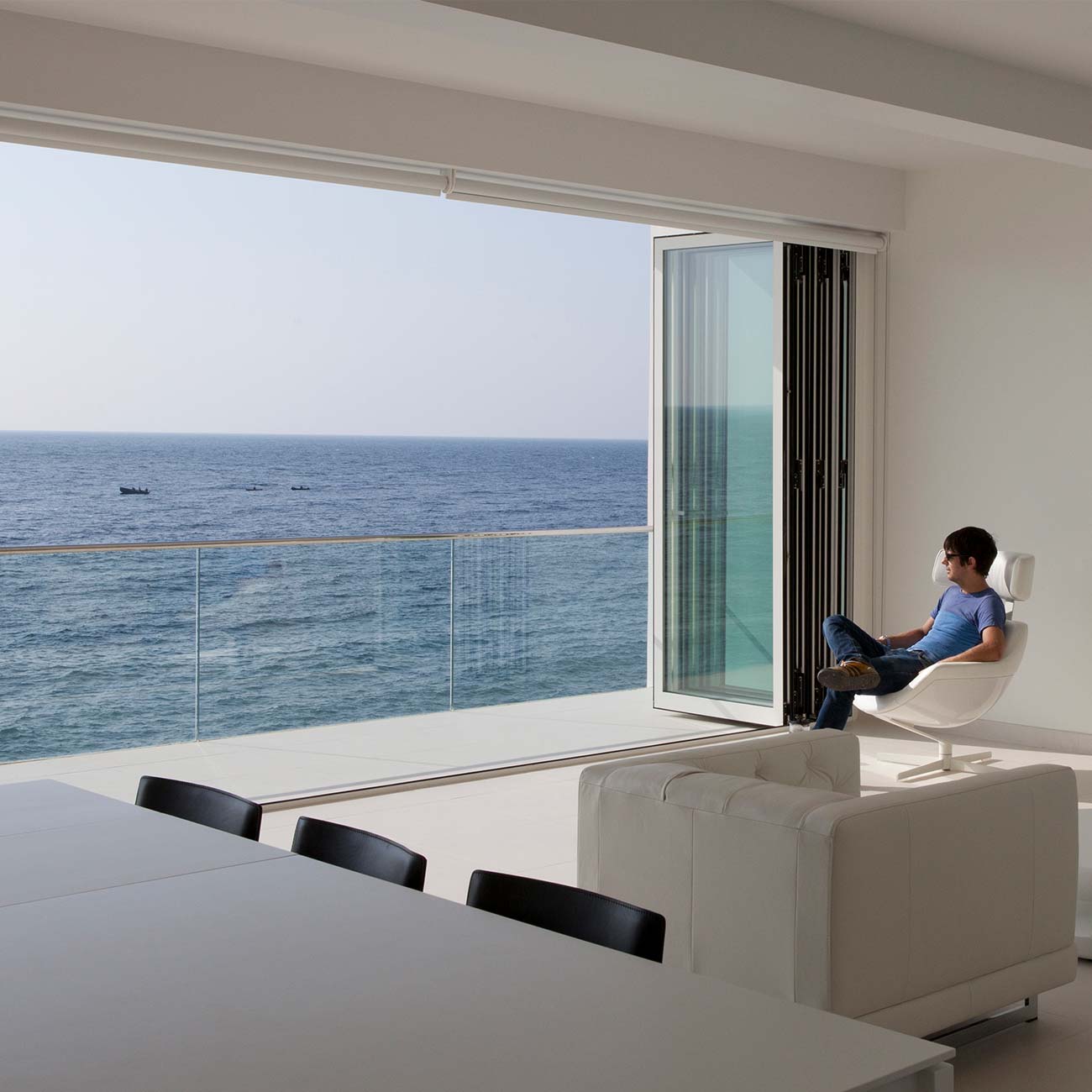 A wide span of Bifold doors fully open to reveal full sea view
