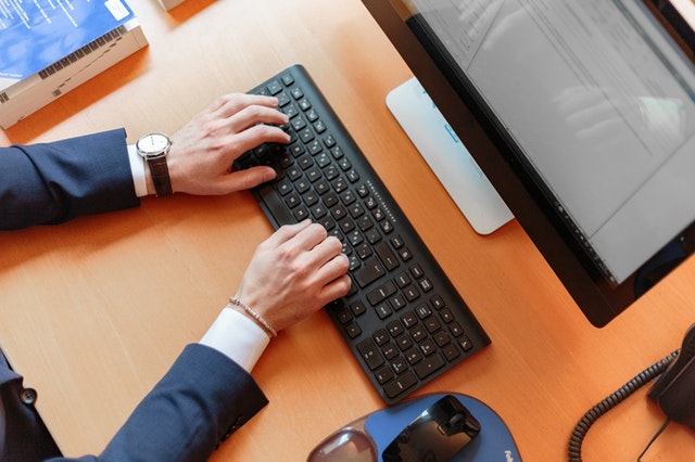 Man in blue suit typing on desk