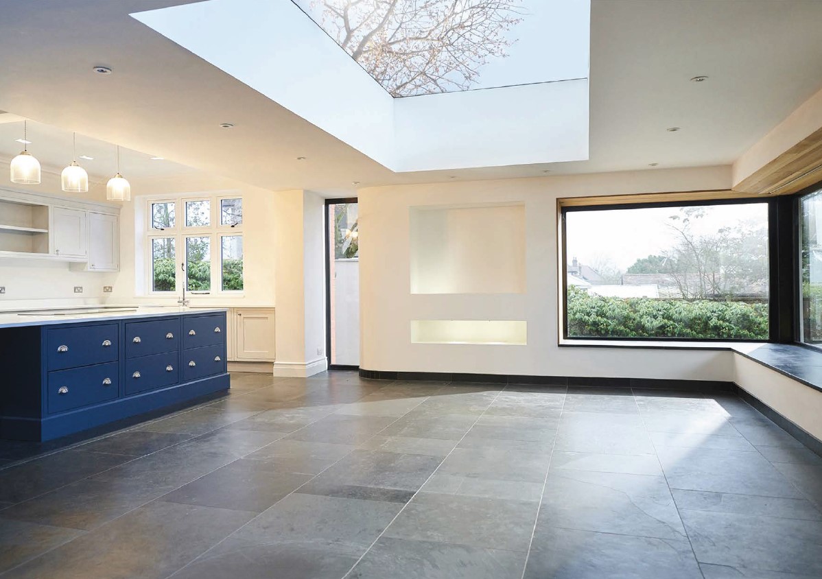 Spacious living area featuring a large blue island, empty shelves, and a central skylight.