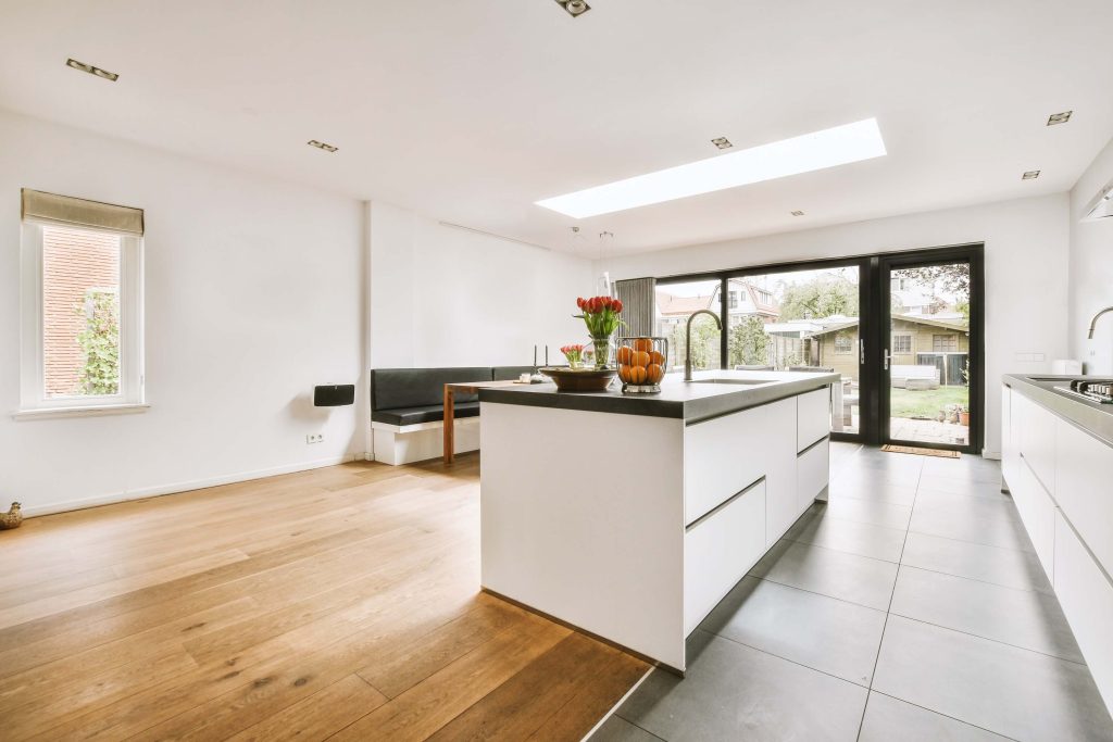 Contemporary kitchen with a skylight, white cabinets, central island, and large glass doors opening to a garden.
