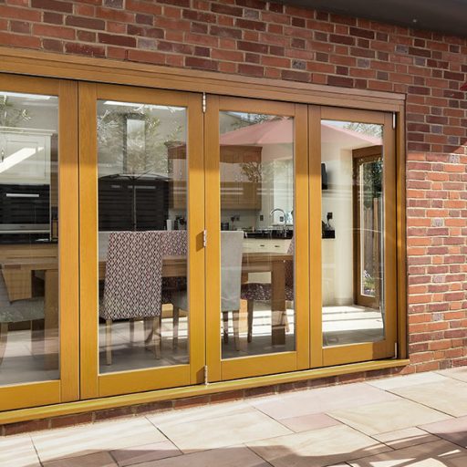 A modern home's exterior with wide wooden bi-fold patio doors leading to a paved outdoor area.
